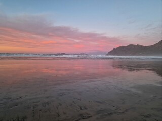 Sunset on Famara Beach, Lanzarote, casts a mesmerizing palette of colors across the sky, blending hues of orange, pink, and purple against the backdrop of the Atlantic Ocean waves.
