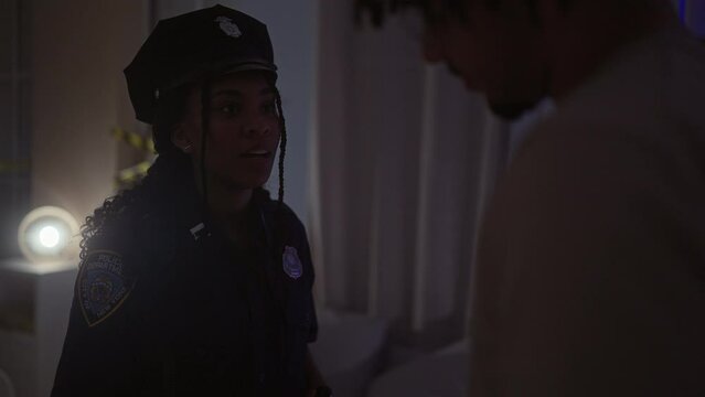 A policewoman from nypd interviews a civilian man indoors, signifying law, order, and civilian interaction.