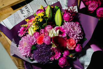 Vibrant Mixed Flower Bouquet Wrapped in Newspaper. An exquisite bouquet of mixed flowers including roses and gerberas wrapped in a creative newspaper wrapping, ideal for gifting.