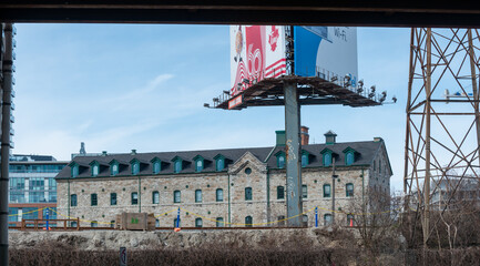 Fototapeta premium road pylon with advertising billboards (Tim Hortons and Bell Canada) with view of heritage building at Distillery District and blue sky in Toronto, Canada