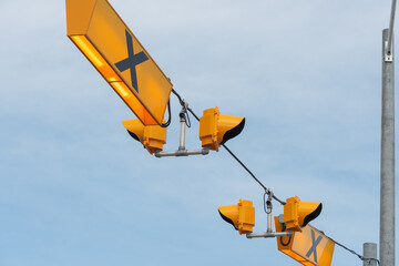 overhanging crosswalk lamps and signs on a blue sky - obrazy, fototapety, plakaty