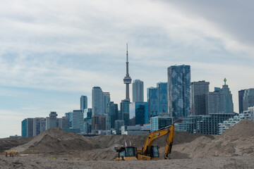 Fototapeta premium construction unfolds at port land with city of Toronto (Canada) skyline on a cloudy sky in the background