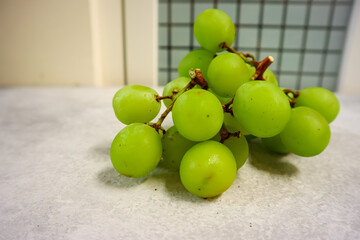 Green muscat grapes in plastic container, close up, grey background