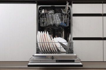 Open modern dishwasher with dirty tableware in kitchen