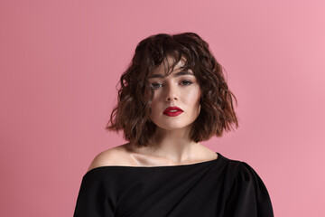 Portrait of beautiful young woman with wavy hairstyle on pink background
