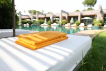 Sunbed near swimming pool at luxury resort, blurred view