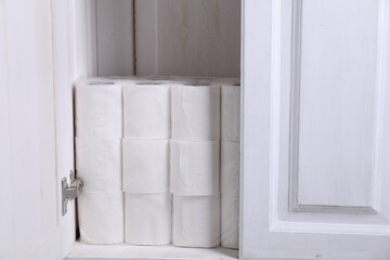 Fototapeta na wymiar Stacked toilet paper rolls in cabinet indoors
