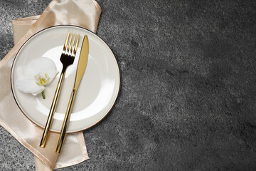 Stylish setting with elegant cutlery on grey table, top view. Space for text