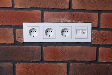 Electric power sockets on brick wall indoors