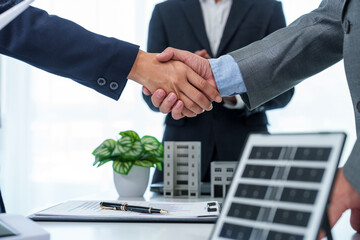 Two business professionals, both clad in suits, firmly shake hands, symbolizing mutual respect, agreement, and the successful culmination of a deal or partnership.