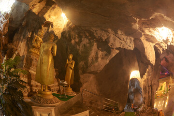 Buddha statues in various postures Enshrined in the famous Tham Khao Yoi Temple. And there are beautiful stalagmites and stalactites. Located at Petchaburi Province in Thailand. - obrazy, fototapety, plakaty