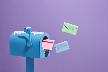 Winter blue mailbox with a flock of letters flying into it