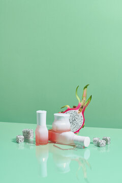 Cosmetic bottles in pastel color arranged with white dragon fruit.