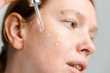 A woman applies lotion to her face