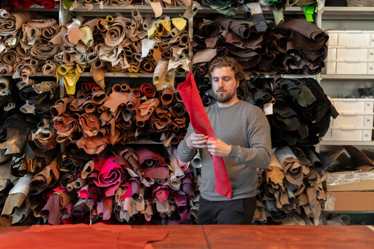 Focused young man standing at table with leather material