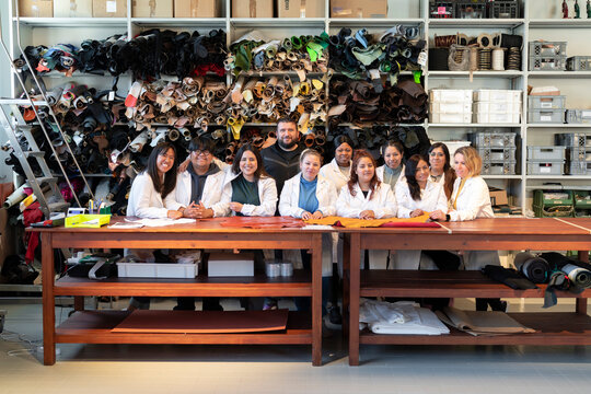 Happy diverse colleagues sitting at tables for group picture
