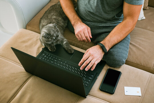 A disabled man with no legs works on a laptop on the couch 