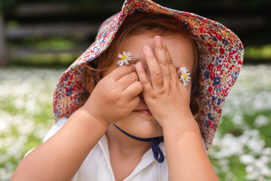 Toddler using daisies flower to replace her eyes