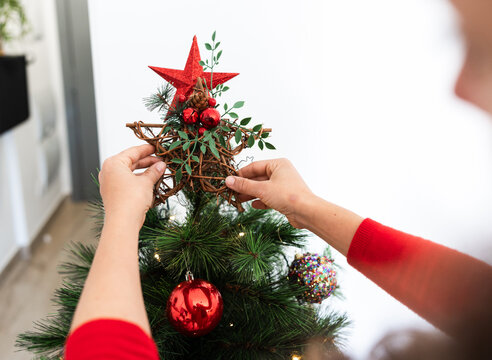 Close-up of woman decorating christmas tree with red star