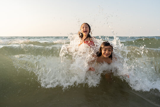 A brother and sister trying to take a wave at the beach