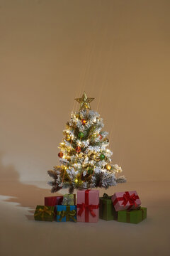 Glowing Christmas tree with presents near warm wall