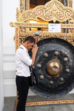 Man praying next to a gong.