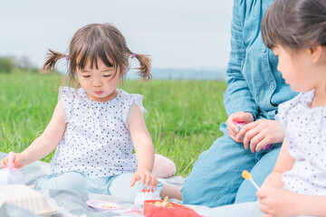 Obraz na płótnie Canvas 野原・公園でおままごとをして遊ぶ子供・姉妹とママ（ピクニック・旅行・キャンプ） 