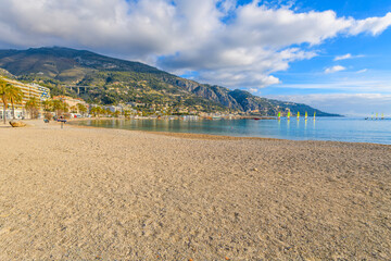 View from the plage des Sablettes beach at Menton, France, looking towards the Italian border and the Garavan port district and town of Ventimiglia, Italy. - obrazy, fototapety, plakaty