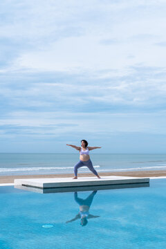 Asian pregnant woman doing yoga by the swimming pool