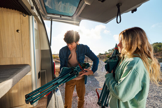 Couple unpacking camping gear from camper