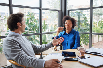 Multiracial colleagues discussing project in workspace