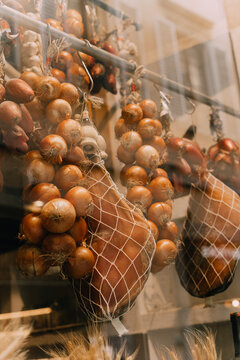 Shop window with hanging whole jamon legs and onions