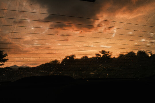car rear window dirty with dust in the sunset
