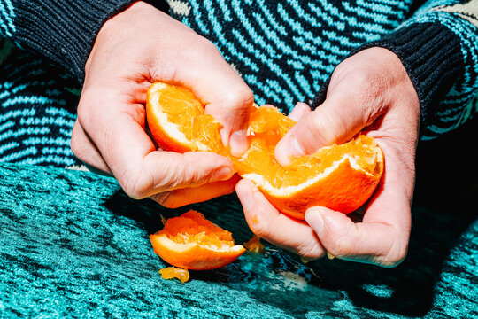 man open an orange with his hands