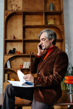 Businessman engrossed in phone conversation reviewing documents