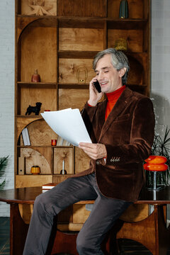 Mature executive having phone call while reviewing documents