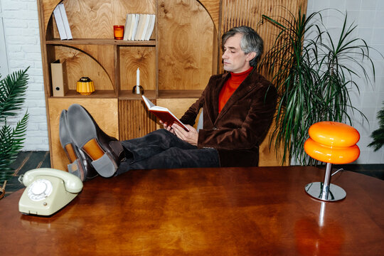Relaxed businessman reading book in stylish office
