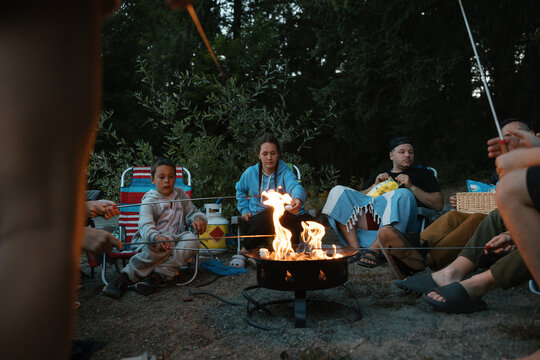 Family and friends around campfire at night.