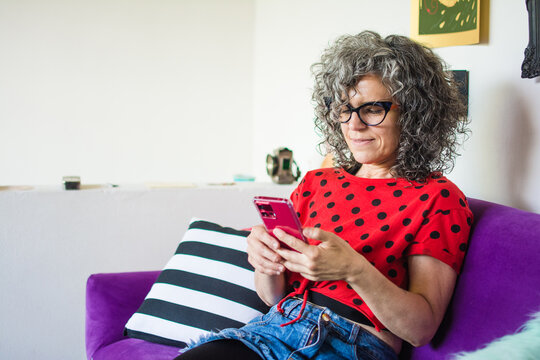 Woman using phone in purple couch
