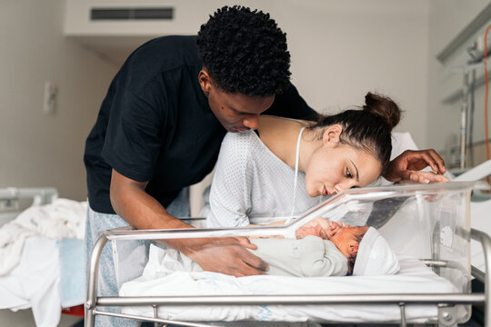 Diverse parents admiring baby after giving birth