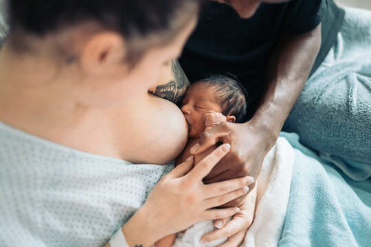 Diverse parents admiring baby after giving birth