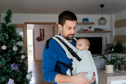 father with baby in sling at home on christmas eve