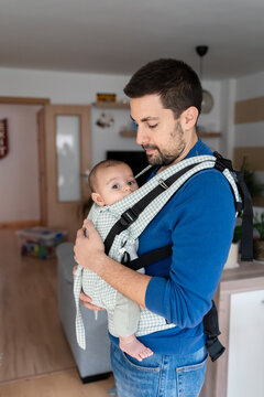 father with baby in sling at home on christmas eve