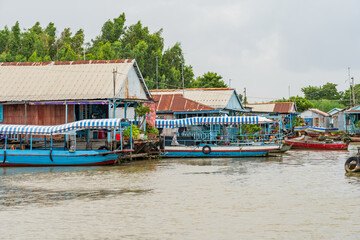 Fototapeta na wymiar Colourful long boats next to houses floating on a river at Chau Doc in Vietnam
