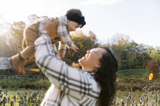Happy smiling mother holding her daughter in arms in autumn.