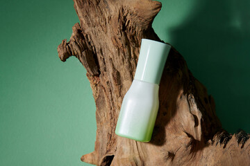 Pump bottle mock up cosmetic product on dry twig on green background