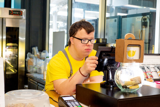 Young guy with Down syndrome works at the cash register