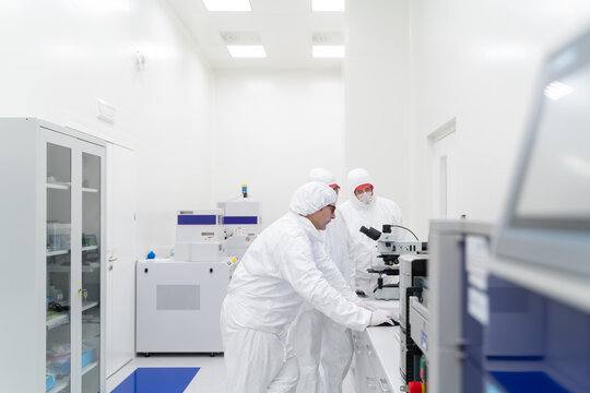 Group Of Scientists Working  With Microscope At Clean Room. 