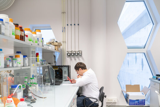 Researcher Taking Notes In Bright Lab Room