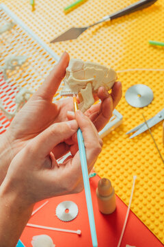 Craftswoman painting miniature toy.